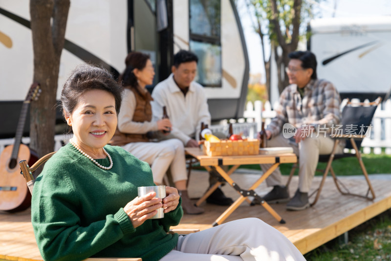 一个老年女人坐在房车露营地喝咖啡