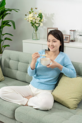 一位年轻女士在家吃早餐喝粥