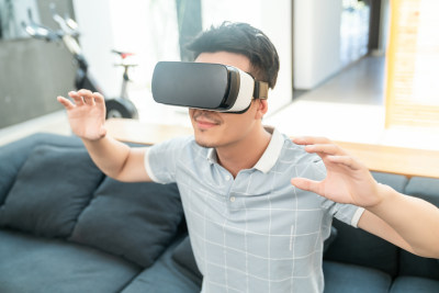 年轻男子在沙发上使用VR眼镜
