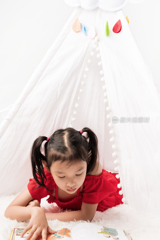 趴在白色帐篷里认真读书的中国女孩