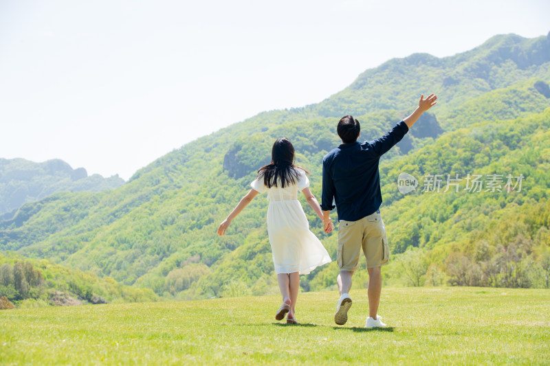 手牵手在郊外旅行的青年情侣