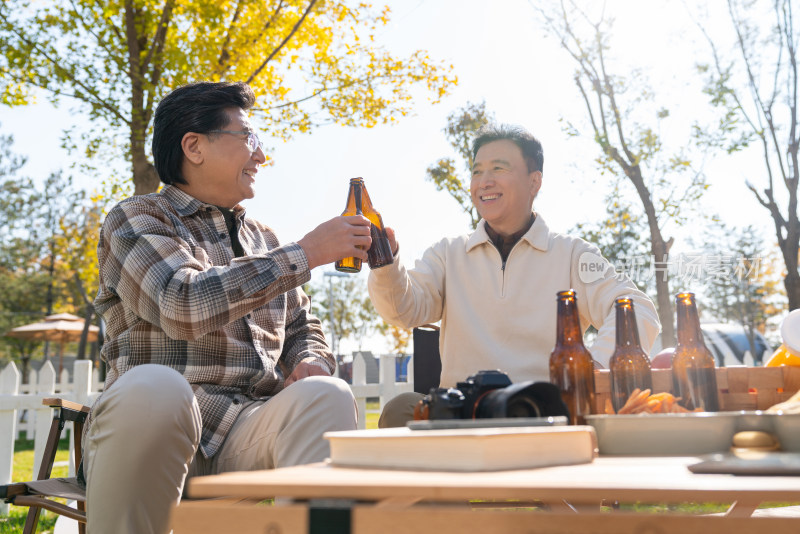 两个老年男人坐在露营地喝啤酒