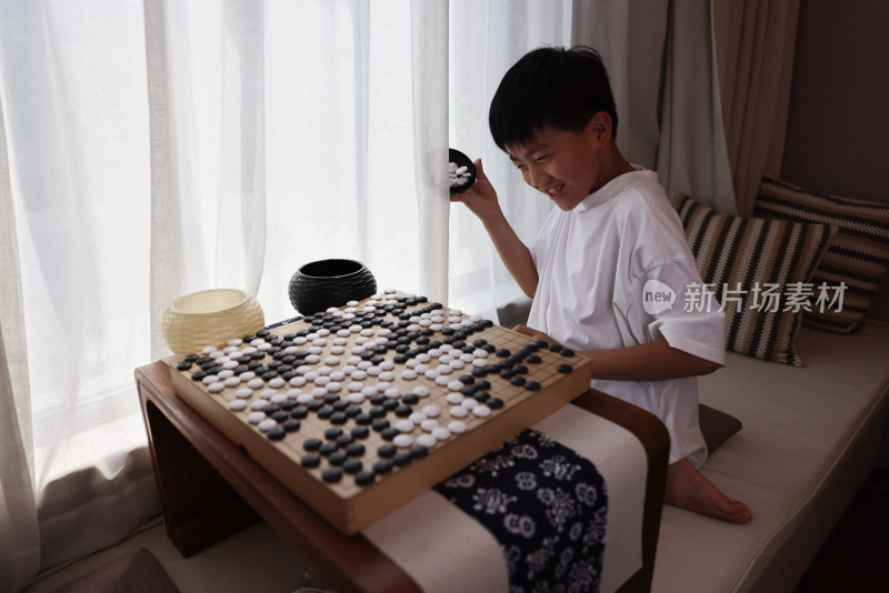 可爱的男孩在窗边下围棋