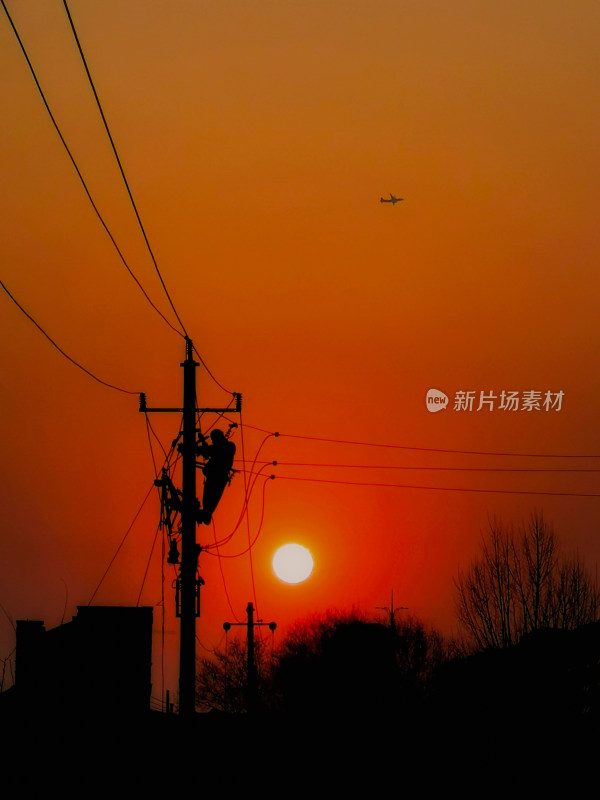 电力工人夕阳下电杆上工作场景