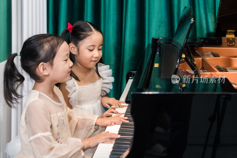 两个正在弹奏钢琴的中国女孩