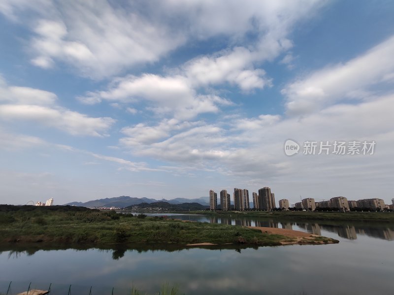 城市中湖泊边林立的高楼及蓝天白云景致