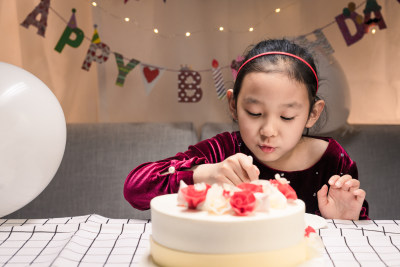 在生日会上吃生日蛋糕的中国女孩