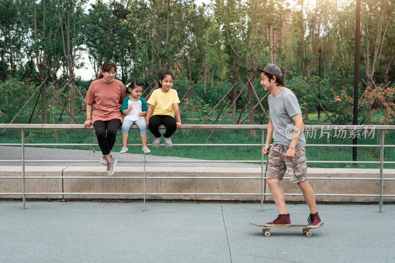 夏天在公园玩滑板的一家人