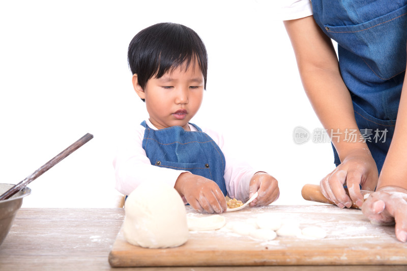 厨房里孩子在学习包饺子旁边妈妈在擀饺皮