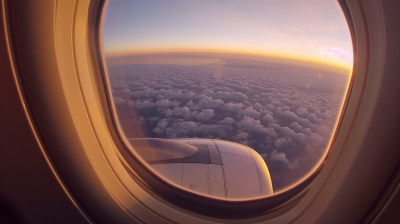 从飞机舷窗拍摄的壮阔云海和远处的日落景致
