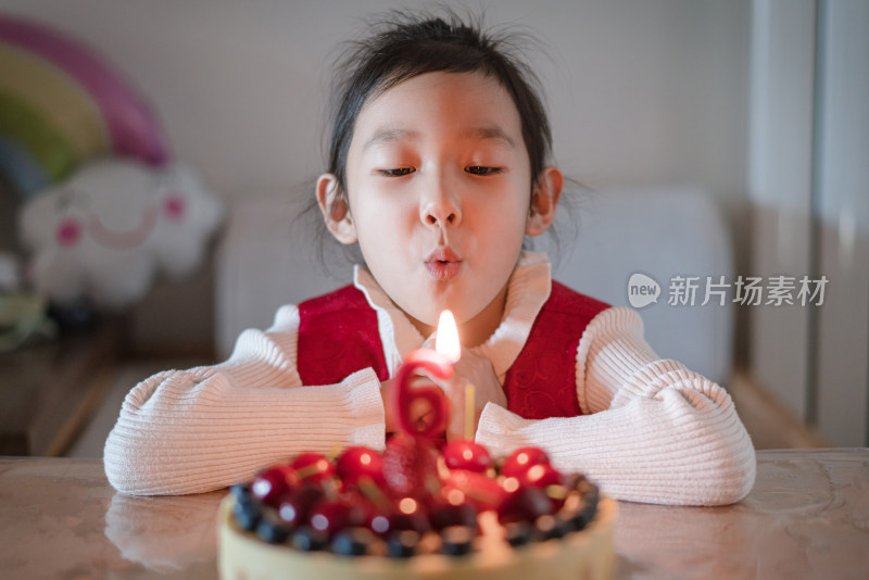 中国女孩吹灭生日蛋糕上的蜡烛