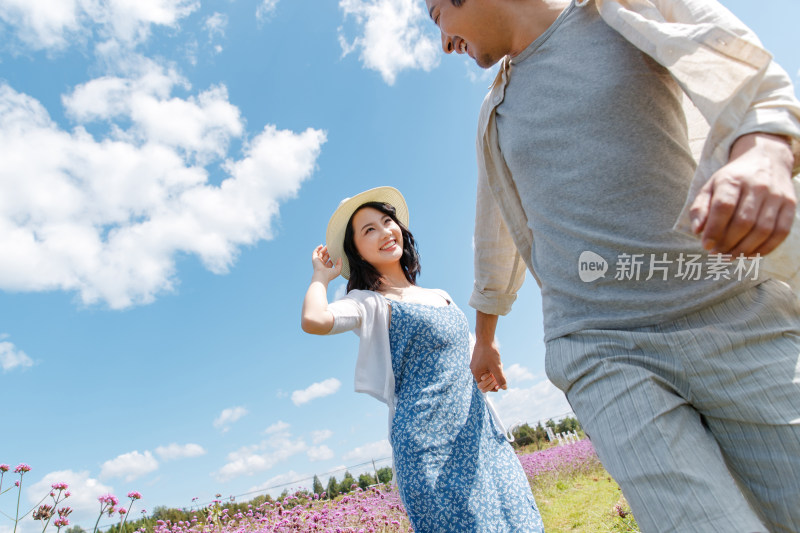 青年夫妇手牵手在花海里奔跑