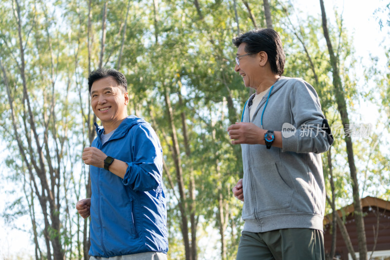 两戴运动手表的中老年男人在树林里跑步健身