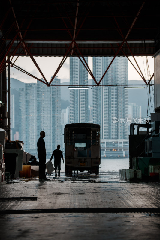 香港仓库内两人与车及城市背景