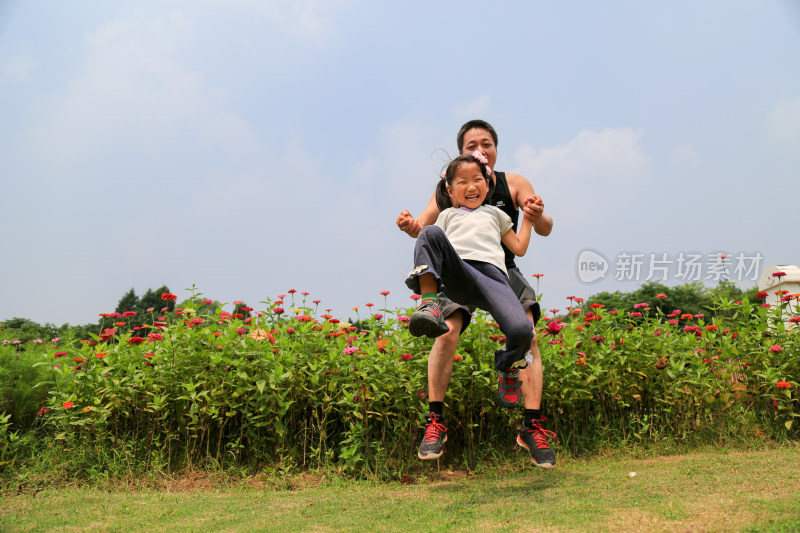 父女在花丛边嬉戏跳跃