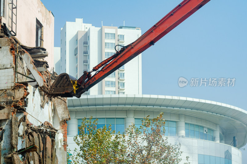 挖掘机的挖斗正在对城市中的老楼进行拆除