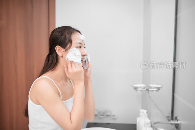 女性在浴室涂抹洁面泡沫