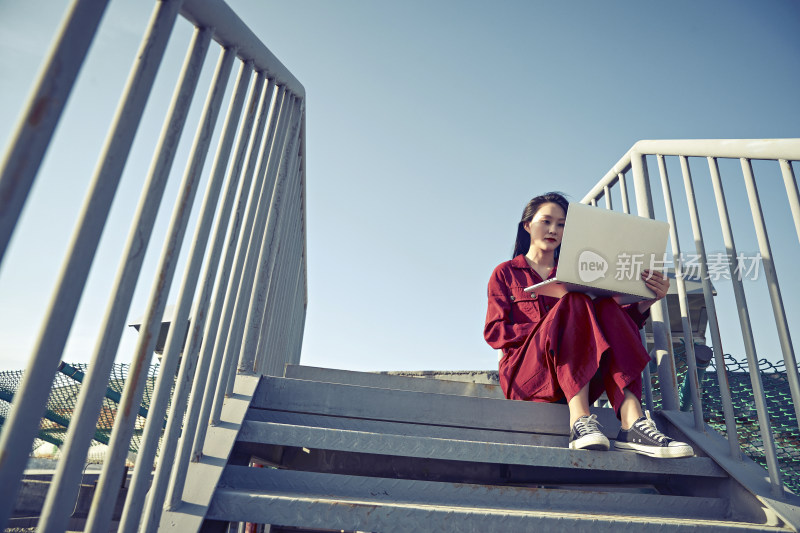 亚洲商务年轻女性在楼顶停机坪使用电脑办公