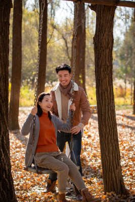 户外秋天幸福的夫妇在荡秋千