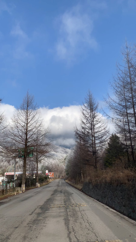 蓝天白云下的雪山和空旷道路