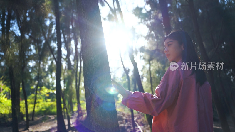 阳光下美女手抚摸树亲近自然感受大自然美好