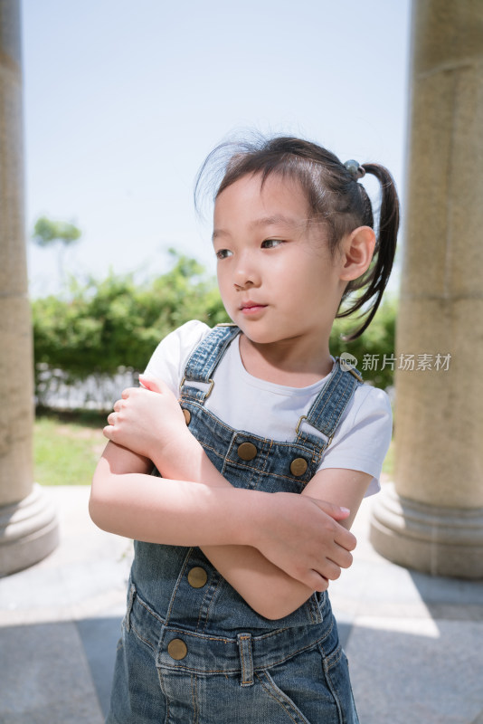 穿背带裤小女孩户外双臂交叉站立