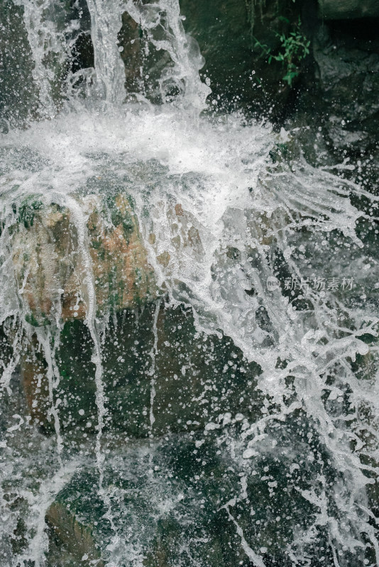 湍急水流撞击岩石溅起水花的景象