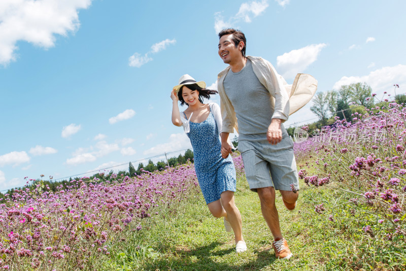 青年夫妇手牵手在花海里奔跑