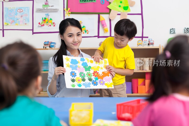 幼儿园女老师和儿童展示手工儿童画