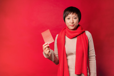 站在红色背景前拿红包的中国女性