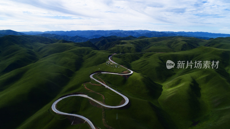 航拍蜿蜒公路穿越绿色山丘的景象