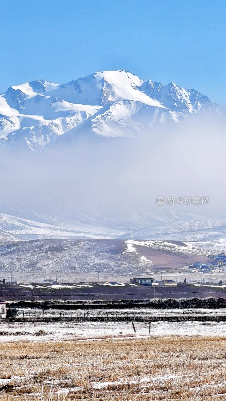 雪山下的开阔土地与错落房屋的景象