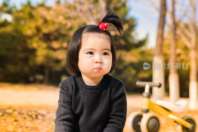 深秋坐在公园落满黄叶的草地上的女孩特写