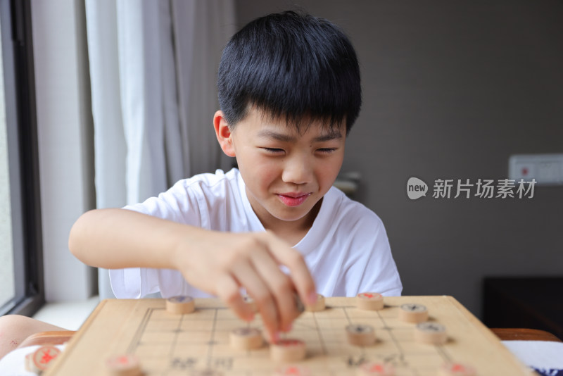 可爱的男孩在窗边下中国象棋