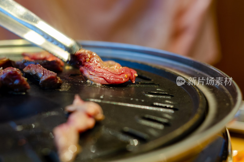 用夹子翻动烤盘上的肉