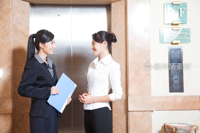 两个年轻商务女士等待电梯