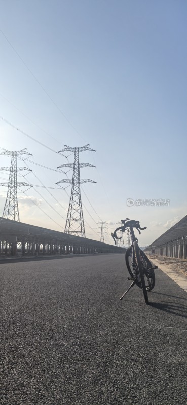 空旷道路旁的自行车与高压电塔