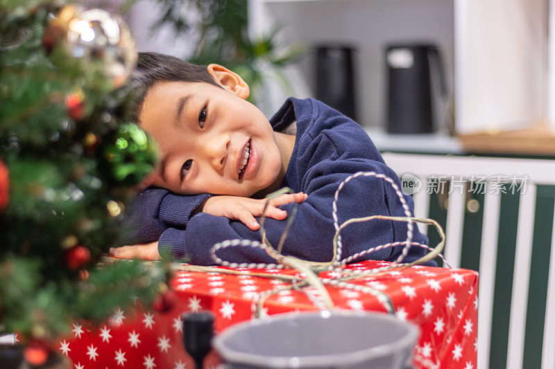 一个小男孩趴在圣诞礼盒上