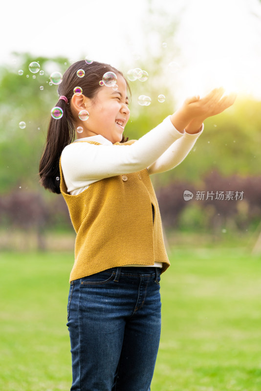 在草坪上玩吹泡泡游戏的女孩