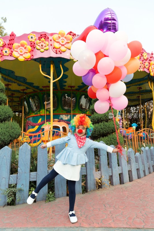 扮小丑的小女孩牵着气球在游乐园
