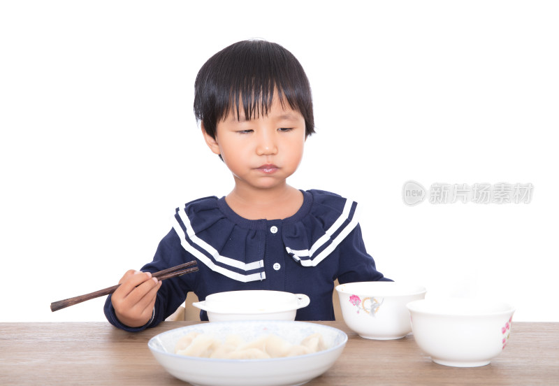 白背景前的餐桌前中国小女孩在自己吃饭