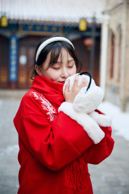 雪后在老城古巷穿着喜庆服饰的亚洲少女