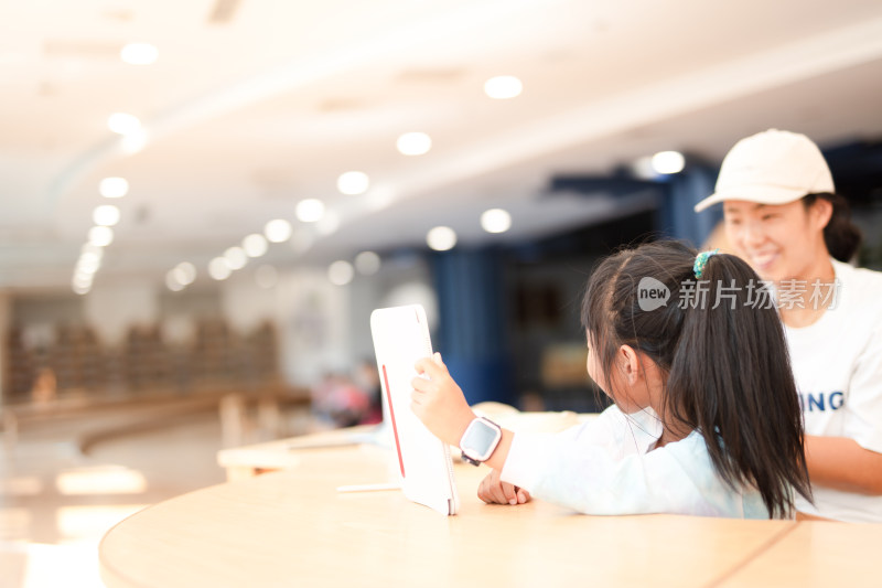 妈妈认真辅导女儿学习在图书馆