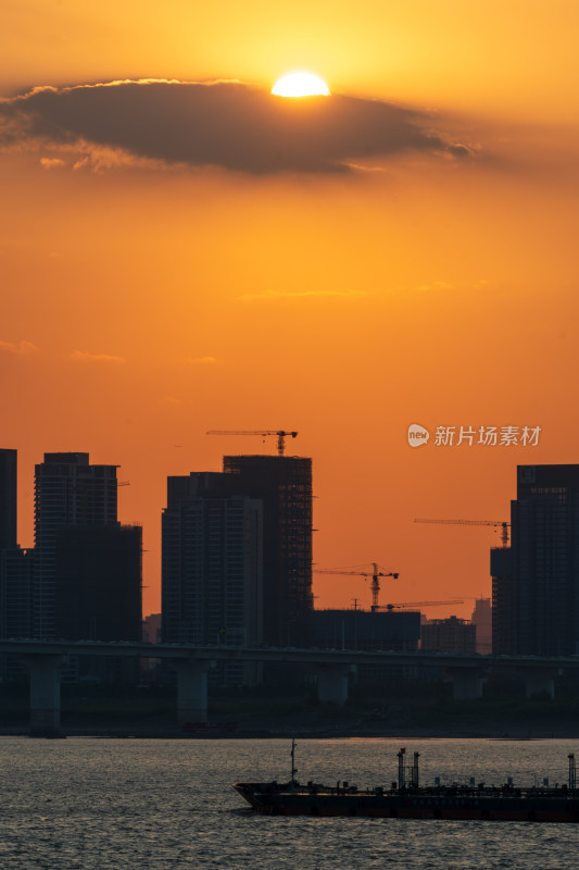 夕阳下的城市剪影与江上船只的景致