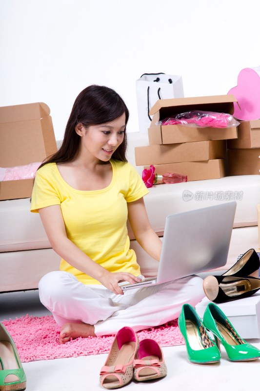 棚拍年轻女人坐在地上使用笔记本电脑上网购物
