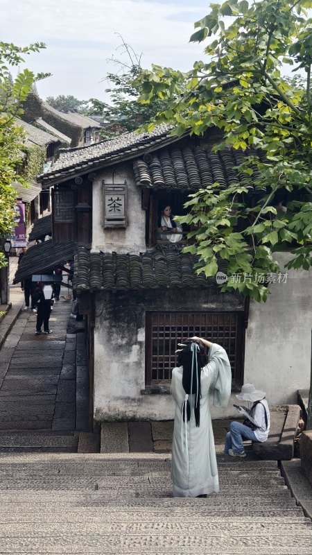 身着古装的女子在古巷中整理发饰