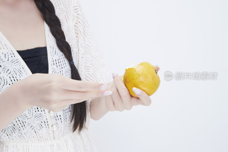 在剥橙子皮的身穿镂空连衣裙的亚洲少女人像