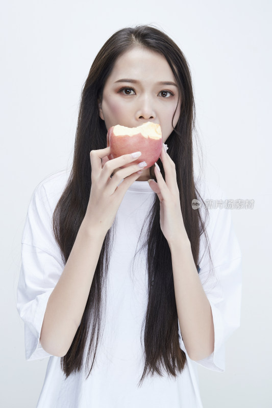 吃苹果的穿白色长T血衫的长发可爱少女人像
