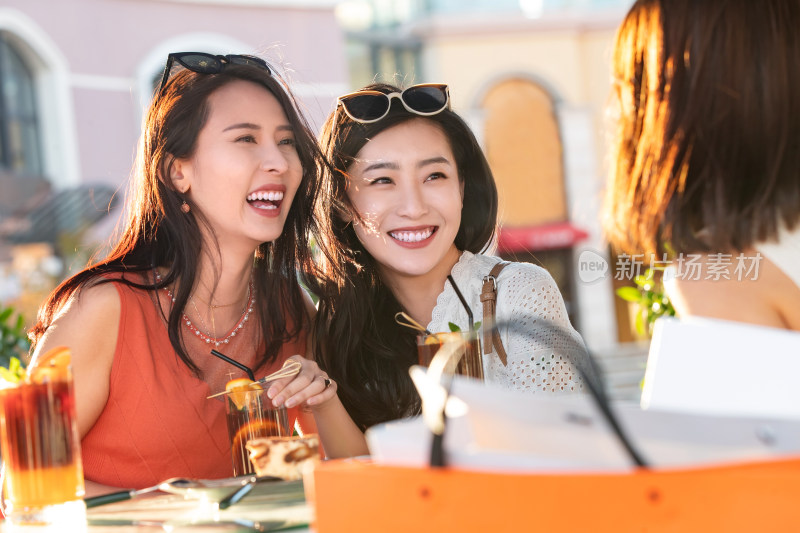 青年女人们坐在露天咖啡馆聊天