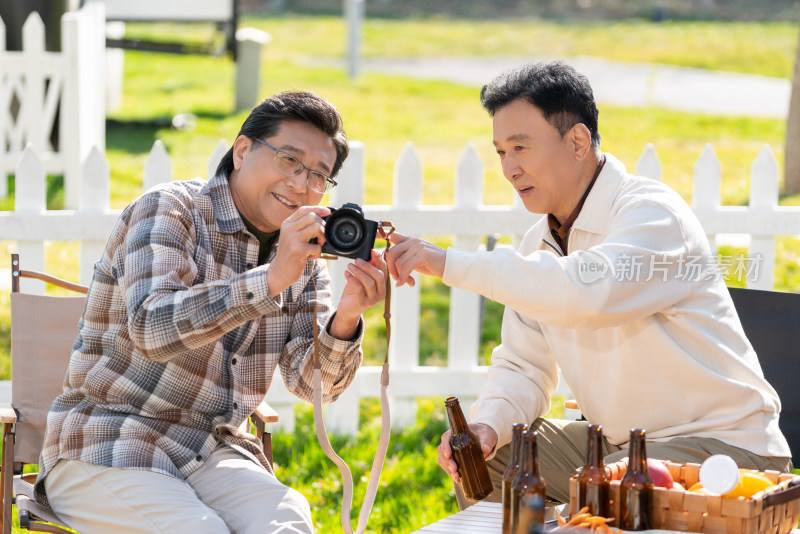 两个老年男人坐在露营地看数码相机